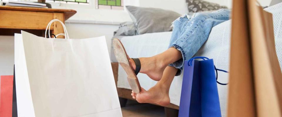 Woman Back From Shopping Trip Surrounded By Bags Lies On Bed