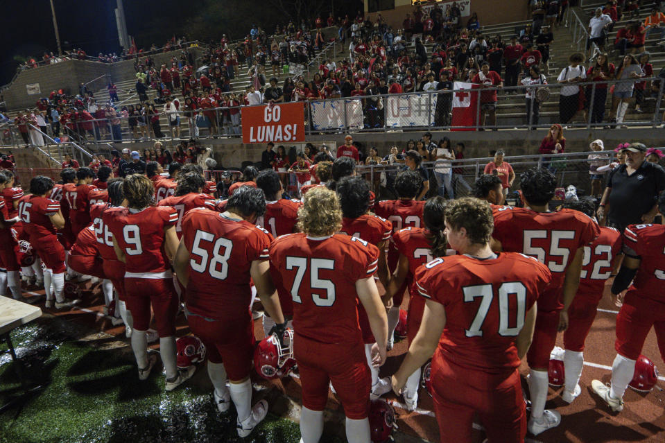 The Lahainaluna High School football team hold hands to thank the fans after a game at Sue D. Cooley Stadium, Saturday, Oct. 21, 2023, in Lahaina, Hawaii. Lahainaluna’s varsity and junior varsity football teams are getting back to normal since the devastating wildfire in August. (AP Photo/Mengshin Lin)