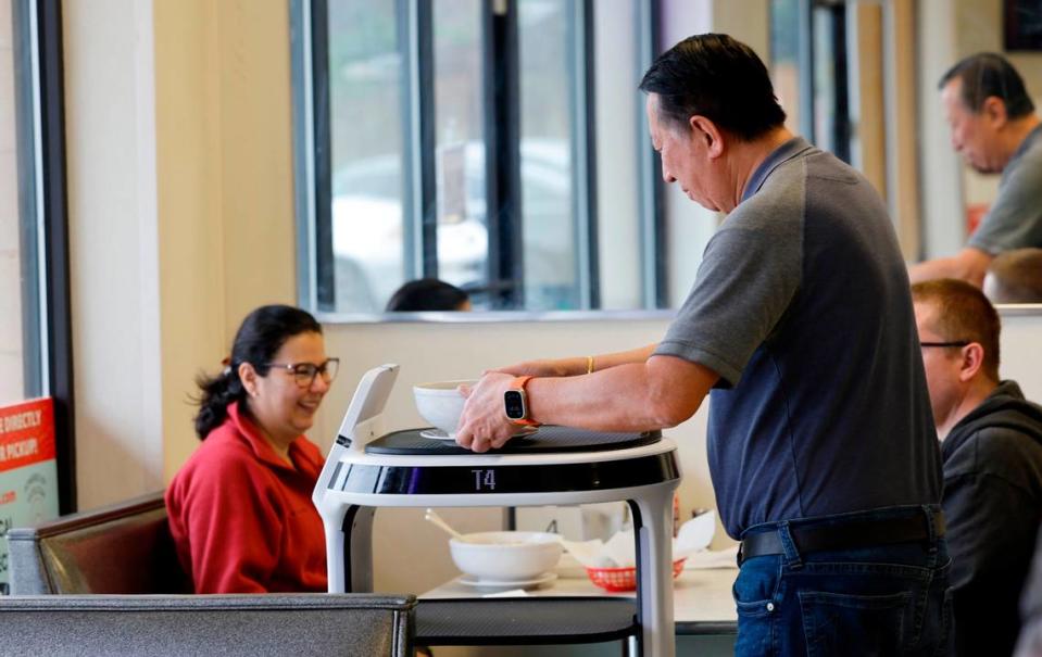 Michael Wongkittiroch, owner of Pho 919, serves dishes from a Servi Delivery Robot.