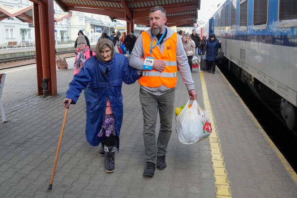 A volunteer helps a Ukrainian refugee walk along a platform at a railway station in Przemysl, Poland, on Friday, March 25, 2022.