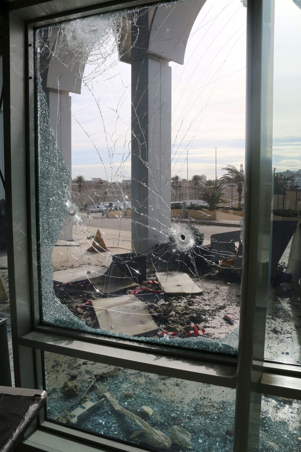 Holes are seen on glass doors at the entrance of Corinthia Hotel where gunmen blew themselves up after storming it, in Tripoli