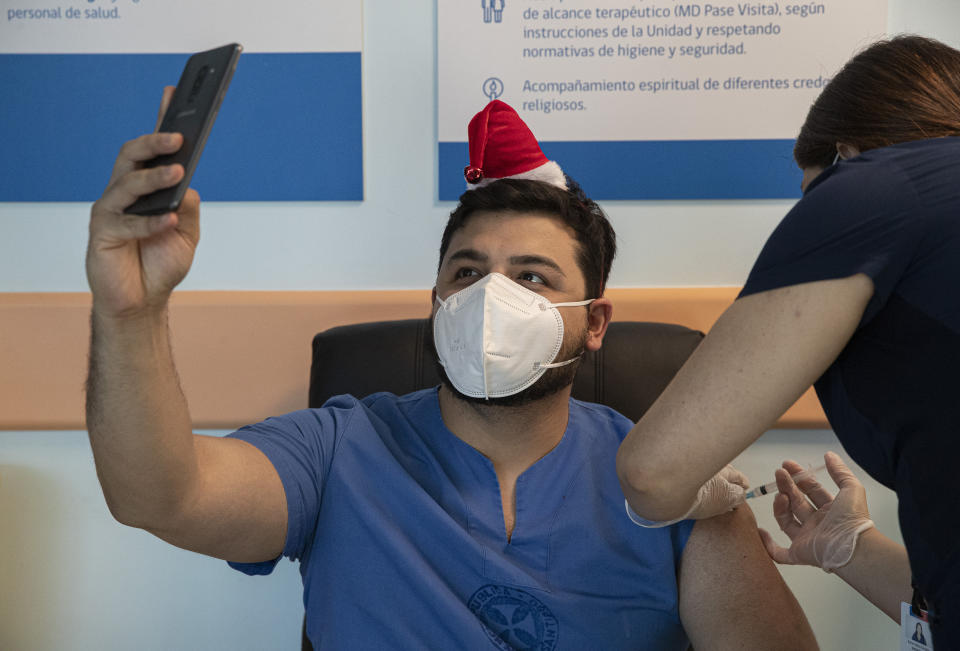 ICU Dr. German Osorio takes a selfie as he gets his COVID-19 vaccine shot at the Posta Central Hospital in Santiago, Chile, Thursday, Dec. 24, 2020, on the same day the first shipment of vaccines arrived from Pfizer and its German partner, BioNTech. (AP Photo/Esteban Felix)