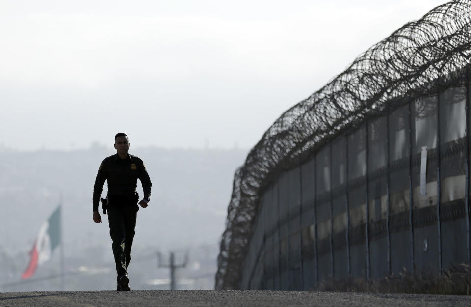 FILE - In this June 22, 2016 file photo, Border Patrol agent Eduardo Olmos walks near the secondary fence separating Tijuana, Mexico, background, and San Diego in San Diego. U.S. President Donald Trump will direct the Homeland Security Department to start building a wall at the Mexican border. (AP Photo/Gregory Bull, file)