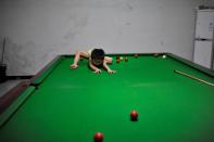 Three-year-old Wang Wuka plays on the table during a break from practising snooker in Xuancheng, Anhui province, September 13, 2013. (REUTERS/Stringer)