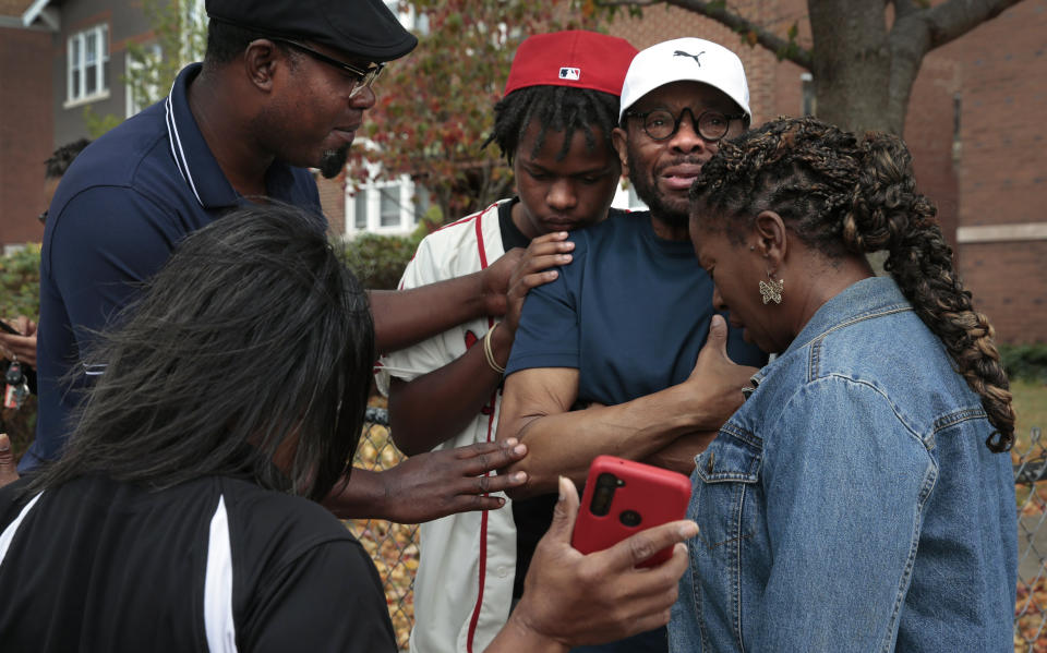 Messiah Miller, 16, center, a junior at Central Visual & Performing Arts High School, prays with his teacher Ray Parks, second from right, following a shooting at the school on Monday, Oct. 24, 2022, in the Southwest Garden neighborhood. "He looked at me, he pointed the gun at me," said Parks, a dance teacher, who came face to face with the gunman. (Robert Cohen/St. Louis Post-Dispatch via AP)