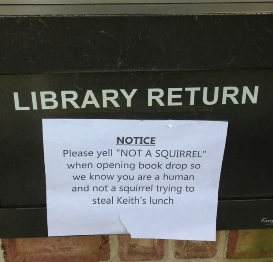 Sign says, Please yell 'NOT A SQUIRREL' when opening book drop so we know you are a human and not a squirrel trying to steal Keith's lunch