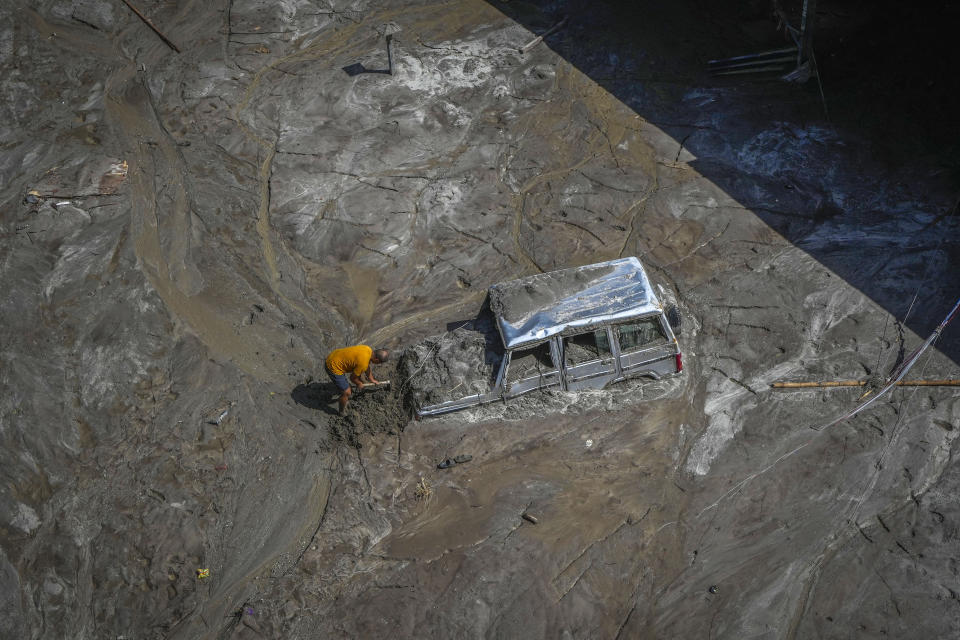 A man digs as he tries to recover a vehicle submerged in mud in the flood affected area along the Teesta river in Rongpo, east Sikkim, India, Sunday, Oct. 8. 2023. Rescuers continued to dig through slushy debris and ice-cold water in a hunt for survivors after a glacial lake burst through a dam in India’s Himalayan northeast, shortly after midnight Wednesday, washing away houses and bridges and forcing thousands to flee. (AP Photo/Anupam Nath)