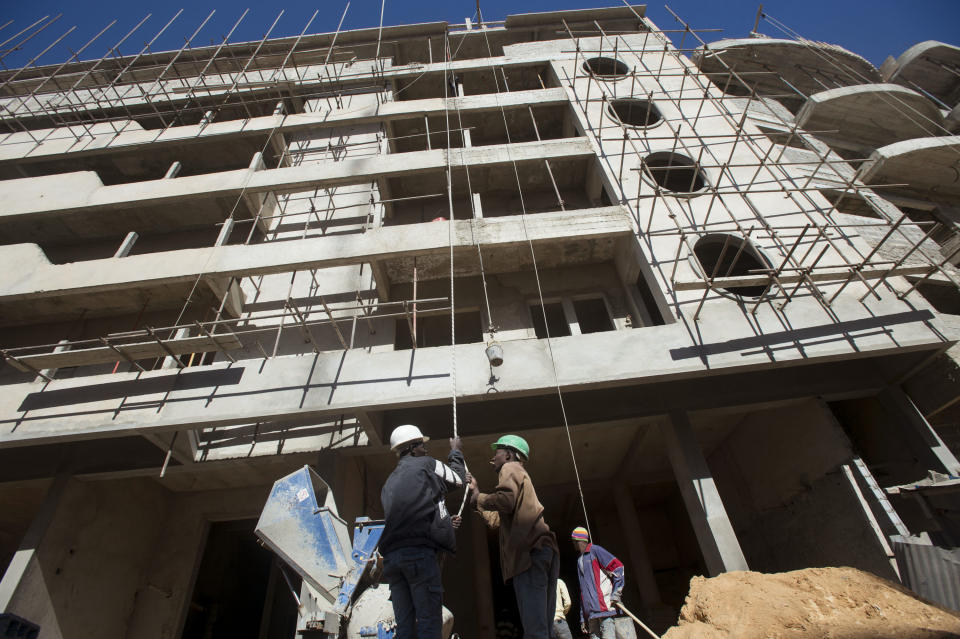 In this photo taken on Tuesday, Feb. 11, 2014, workers lift cement by hand during the construction of a residential building in Dakar, Senegal. President Macky Sall successfully ran on a campaign to lower living costs and now a new law mandates across-the-board rent reductions in Senegal, although everybody knows enforcement will be tricky and some landlords will defy the threat of prison sentences as they fail to comply with the reductions after decades of increases.(AP Photo/Sylvain Cherkaoui)