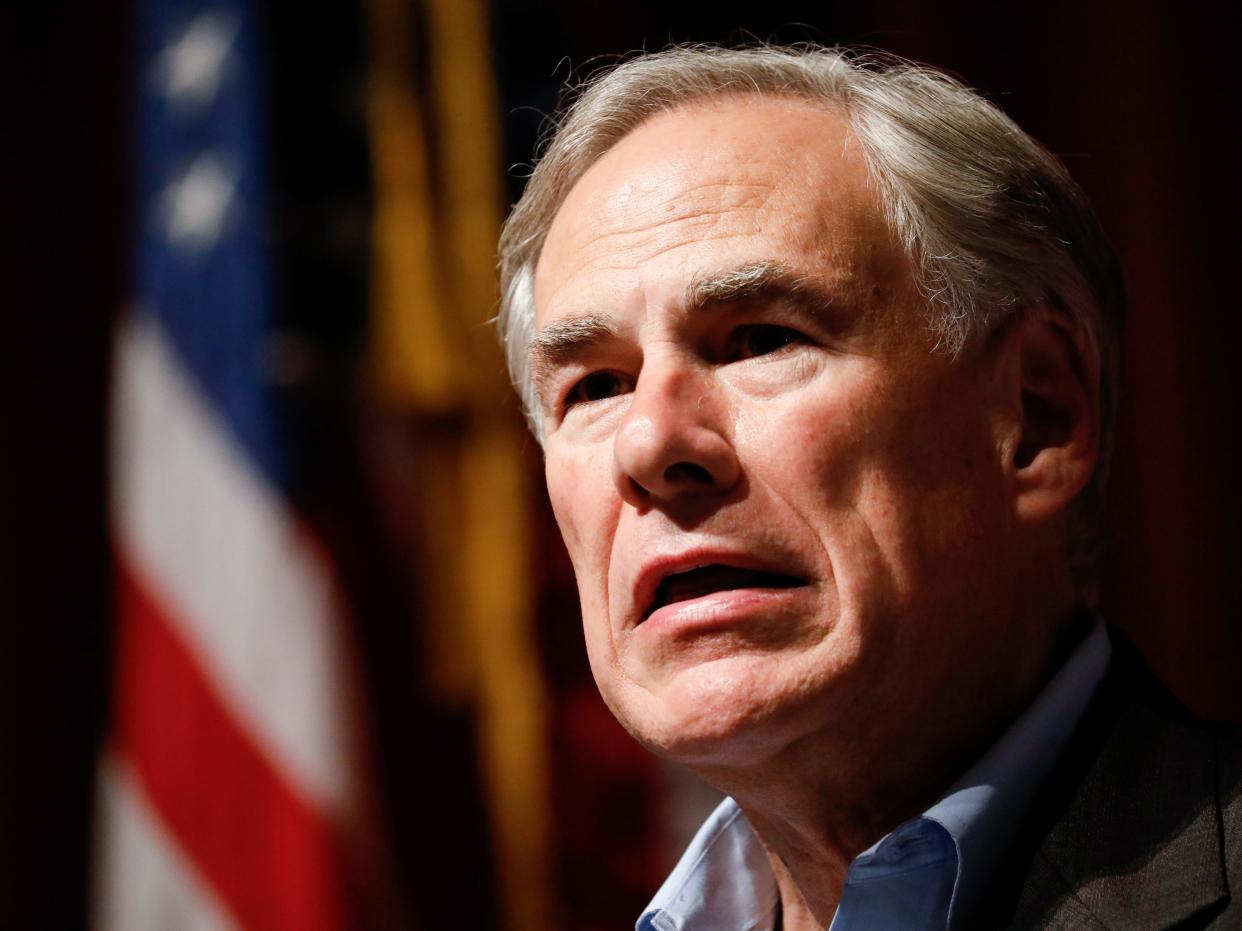 Texas Governor Greg Abbott stares with an American flag in the background.