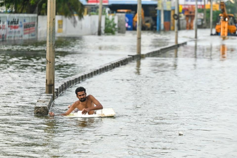 A man wades across a flooded street after heavy rains in Chennai (AFP via Getty Images)