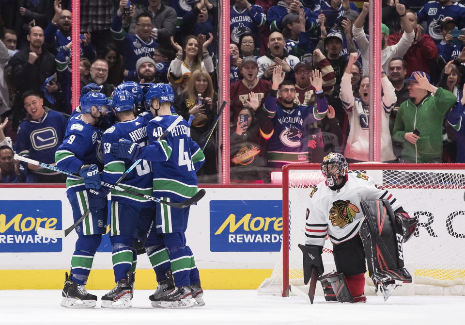 Vancouver Canucks' J.T. Miller, Bo Horvat, Brandon Sutter and Elias Pettersson, from left, celebrate Horvat's goal against Chicago Blackhawks goalie Corey Crawford during the first period of an NHL hockey game Wednesday, Feb. 12, 2020, in Vancouver, British Columbia. (Darryl Dyck/The Canadian Press via AP)