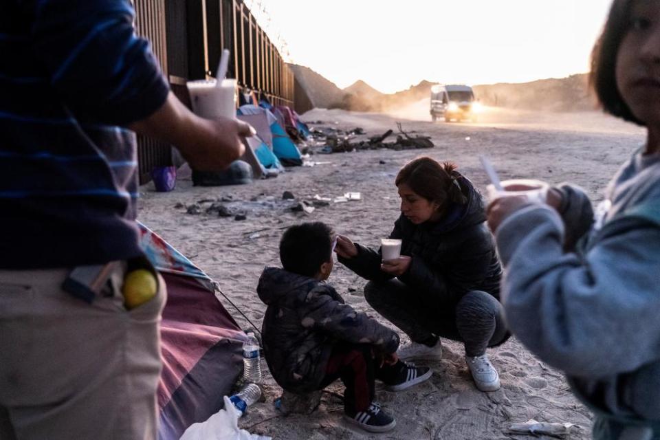 A migrant mother feeds her son while waiting to be transported by border patrol in Jacumba Hot Springs, California, on 11 November 2023.