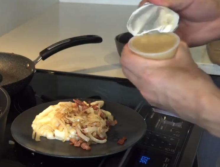 opening up applesauce over mac and cheese with onions and bacon