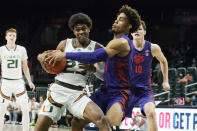 Miami guard Kameron McGusty (23) drives to the basket as Clemson guard David Collins (13) defends during the first half of an NCAA college basketball game, Saturday, Dec. 4, 2021, in Coral Gables, Fla. (AP Photo/Marta Lavandier)