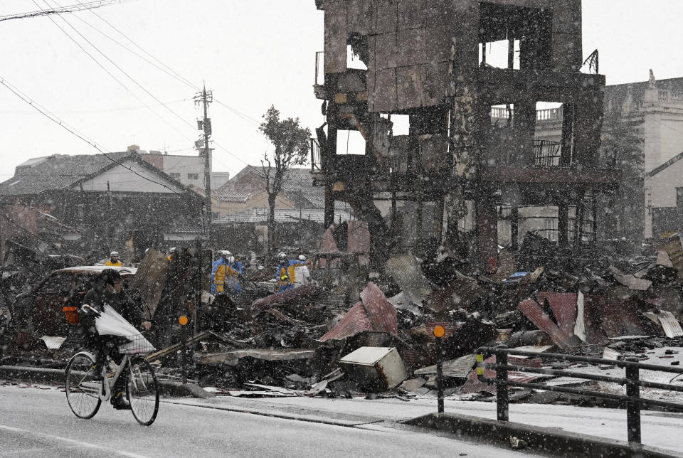 Snow falls as a search operation is continued at a burnt market in Wajima, Ishikawa prefecture, Japan Sunday, Jan. 7, 2024. A major earthquake slammed western Japan on Jan. 1, killing scores of people, toppling buildings and setting off landslides. (Kyodo News via AP)