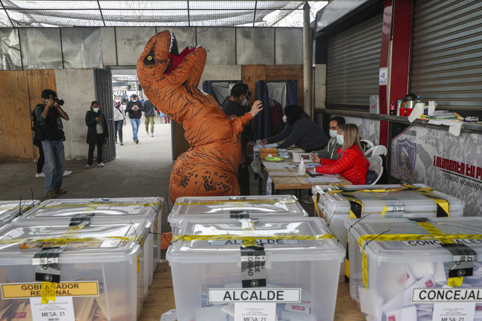 Una persona con un traje de dinosaurio vota durante el segundo día de la elección de la Convención Constitucional para seleccionar a los miembros de la asamblea que redactarán una nueva constitución, en Santiago, Chile, el domingo 16 de mayo de 2021. (AP Foto/Esteban Felix)