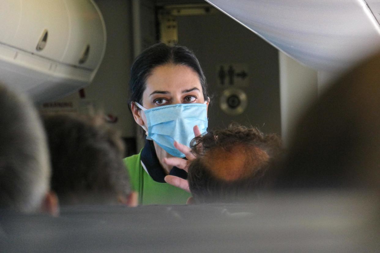 Close up portrait of a female air stewardess cabin crew during the flight. Flying in an Olympic Air De Havilland Canada DHC-8-400 Turboprop aircraft during the Covid-19 Coronavirus pandemic era with obligatory usage of face masks for the passengers. The flight crew, female air stewardess are wearing also safety equipment such as facemasks and gloves while the meals are changed and disinfecting napkin is provided.  The domestic flight route is from Athens ATH LGAV Airport, the Greek capital to the islands of Cyclades. Greeks and foreign pax travel to popular islands such as Mykonos or Santorini after the Greek Government lifted the traffic ban, lockdown quarantine measures for tourists, easing generally the measures to relaunch the tourism season, with more Covid tests at the airports and the entry points to Greece. Although there are still some countries whose citizens are banned due to the increased numbers of Coronavirus cases. July 14, 2020 (Photo by Nicolas Economou/NurPhoto via Getty Images)
