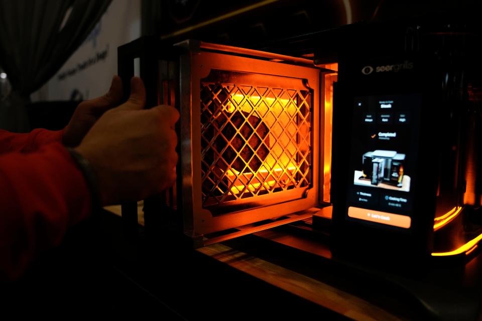 An exhibitor provides a demonstration of the Perfecta AI grill by Seer Grills during the CES tech show Wednesday, Jan. 10, 2024, in Las Vegas.