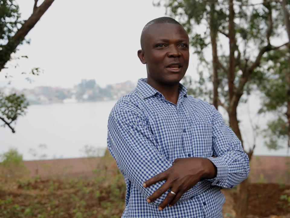 Ali N'Simbo stands with his arms crossed, with a body of water behind him.