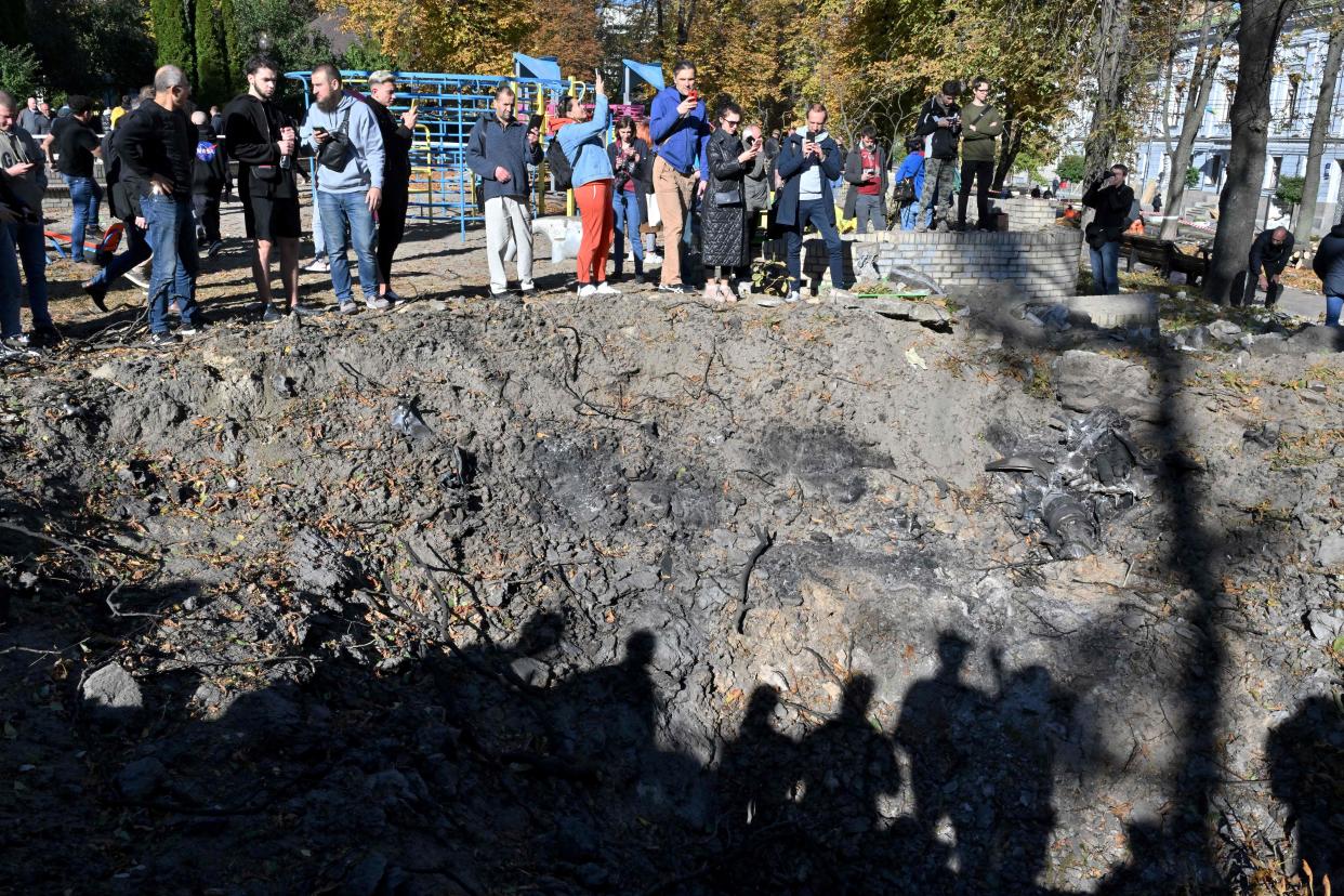 People stand by a rocket crater next to a child playground in central Kyiv on October 10, 2022 after Ukraine's capital was hit by multiple Russian strikes early on today, the first since late June. - The head of the Ukrainian military said that Russian forces launched at least 75 missiles at Ukraine, with fatal strikes targeting the capital Kyiv, and cities in the south and west. (Photo by Sergei SUPINSKY / AFP) (Photo by SERGEI SUPINSKY/AFP via Getty Images)