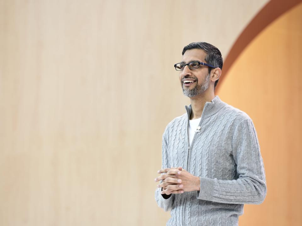 Sundar Pichai, CEO of Google, wears a gray sweater and smiles on stage during a presentation at Google I/O in Mountain View, California, on May 10, 2023.