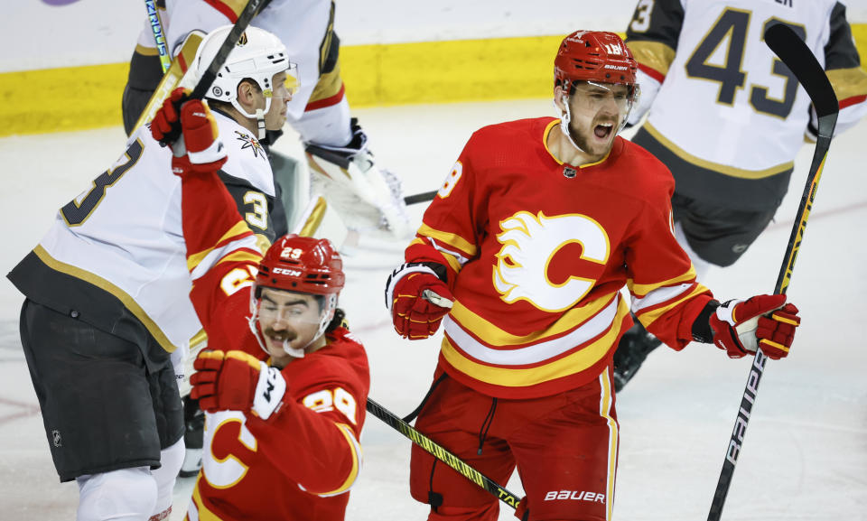 Vegas Golden Knights defenseman Brayden McNabb, left, looks on as Calgary Flames forward A.J. Greer, right, celebrates his goal during the third period of an NHL hockey game in Calgary, Alberta, Monday, Nov. 27, 2023. (Jeff McIntosh/The Canadian Press via AP)