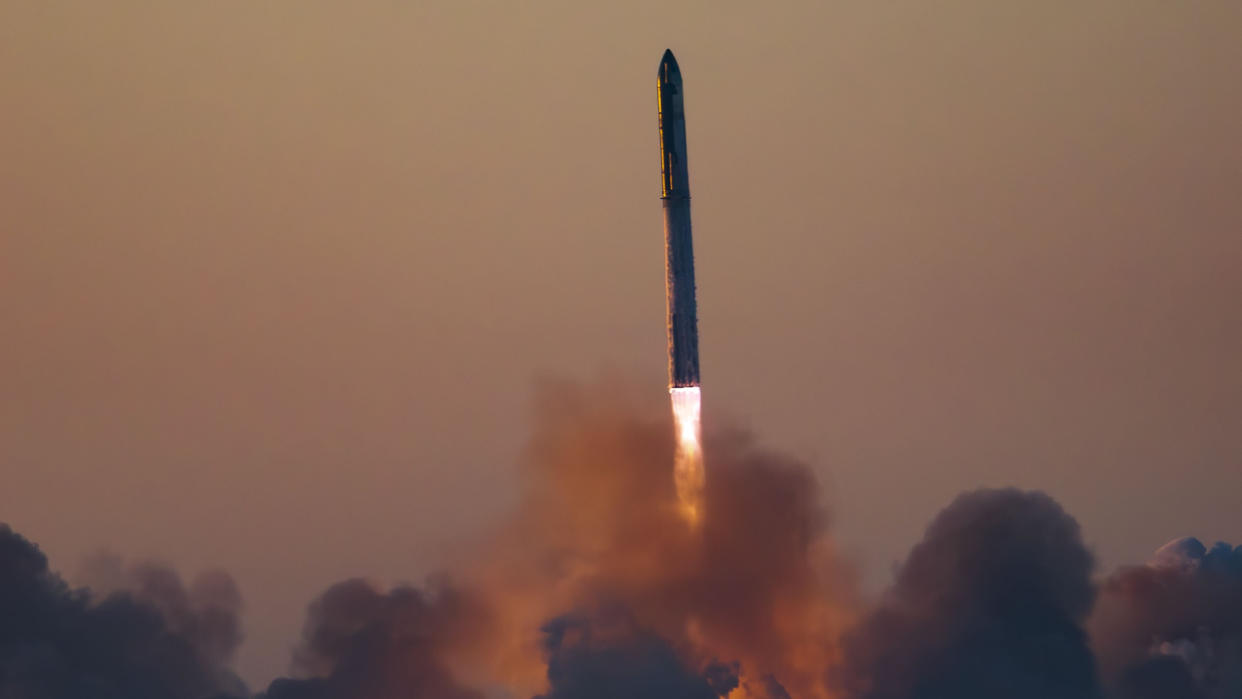  A massive rocket lifts off above a plume of fire at sunrise. 