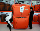 Staff members try to move a huge trolley case during the 100th Chinese Export Commodities Fair in Guangzhou, south China's Guangdong province October 15, 2006. This trolley case has been certified as the world's largest by the Guinness World Records and measures 175cm (5ft 9in) by 115cm (3ft 9.3in) by 46cm (1ft 6.1in) thick. REUTERS/Alvin Chan