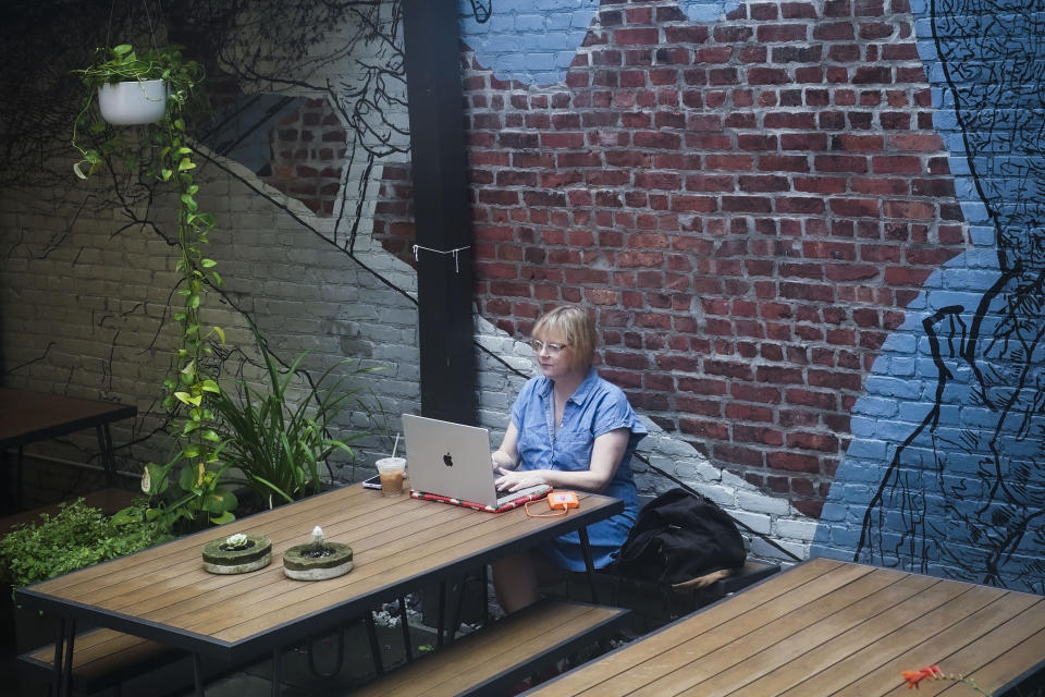 Wedding photographer Jonica Moore works from a Brooklyn cafe where she sometimes edits her wedding assignments, Friday, July 21, 2023, in New York. Moore said that adding more social content to packages will likely require her to hire another person to help with weddings. (AP Photo/Bebeto Matthews)