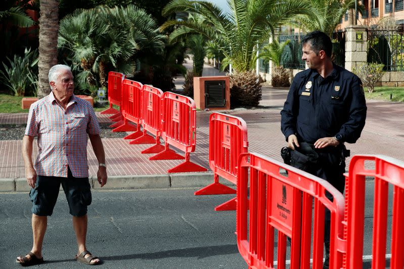 A police officer and a man are seen in H10 Costa Adeje Palace's area, which is on lockdown after cases of coronavirus have been detected there in Adeje