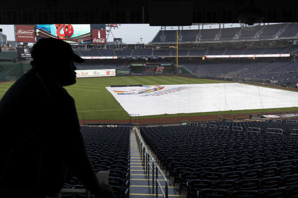 A worker looks at the tarp covering the field before a baseball game between the Washington Nationals and the San Francisco Giants at Nationals Park, Thursday, June 10, 2021, in Washington. The game was postponed until Saturday June 12th. (AP Photo/Alex Brandon)