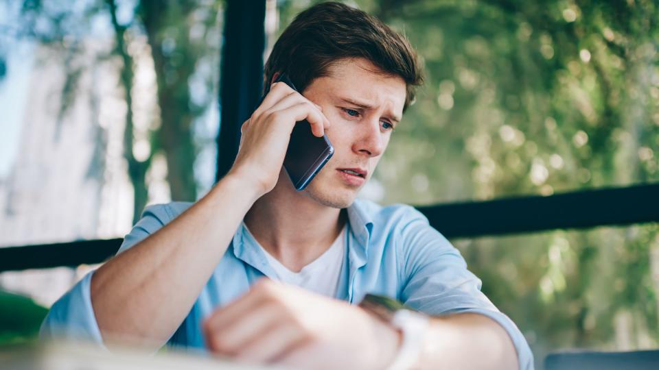 Frustrated young man 20 years old unhappy with bad news head during phone call on smartphone device.