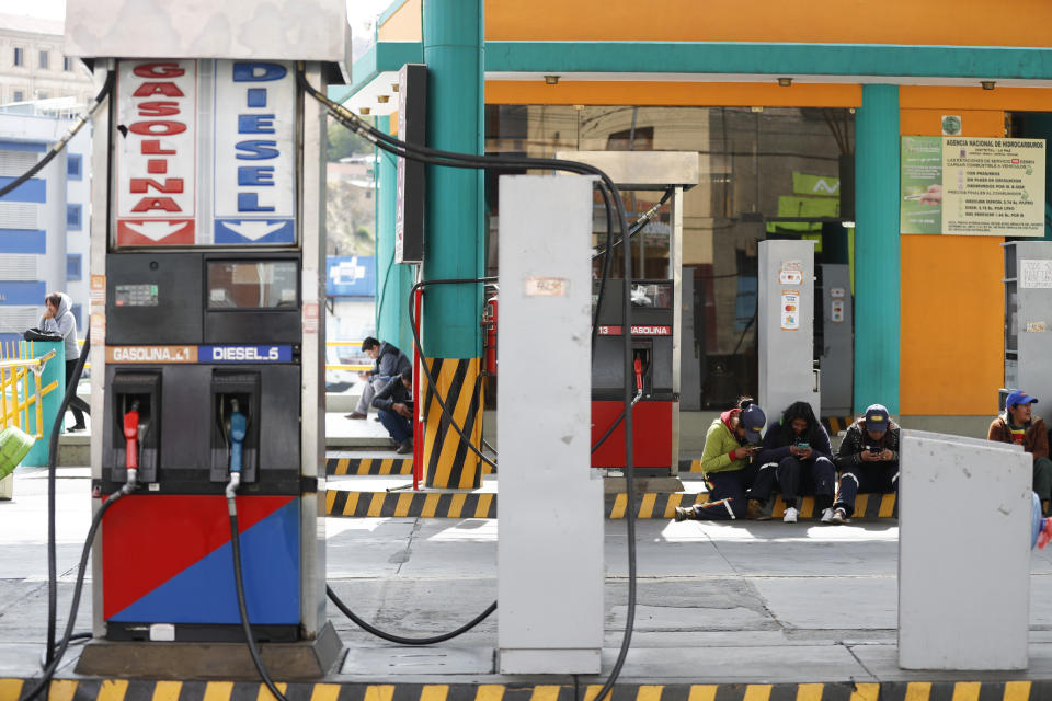 Workers sit at a gas station in La Paz, Bolivia, Thursday, Nov. 14, 2019. Gas stations have run out of fuel as the result of followers of former President Evo Morales blocking the main highway. (AP Photo/Natacha Pisarenko)