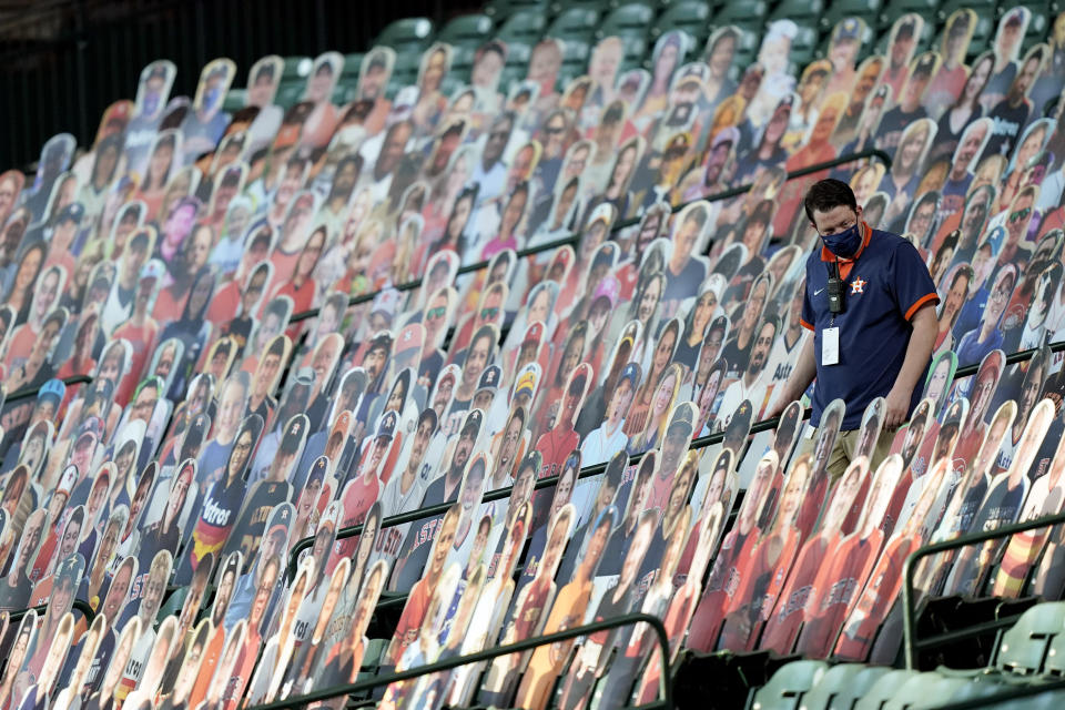 A Houston Astros employee looks for a foul ball in the stands among cutouts of fans during the fourth inning of a baseball game against the Seattle Mariners Saturday, Aug. 15, 2020, in Houston. (AP Photo/David J. Phillip)