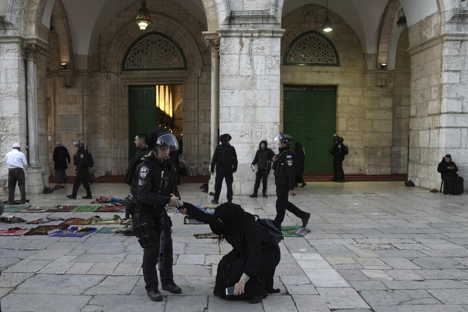 An Israeli policewoman pulls up a woman worshipper who was sitting on the ground at the Al-Aqsa Mosque compound following a raid at the site during the Muslim holy month of Ramadan in the Old City of Jerusalem, Wednesday, April 5, 2023. Palestinian media reported police attacked Palestinian worshippers, raising fears of wider tension as Islamic and Jewish holidays overlap.(AP Photo/Mahmoud Illean)