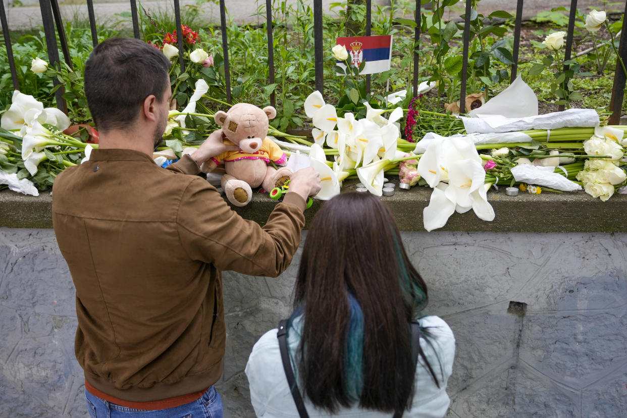 People lay flowers for the victims in front of the Vladimir Ribnikar school in Belgrade, Serbia, Thursday, May 4, 2023. A 13-year-old opened fire Wednesday at his school in Serbia's capital. He killed eight fellow students and a guard before calling the police and being arrested. Six children and a teacher were also hospitalized. (AP Photo/Darko Vojinovic)