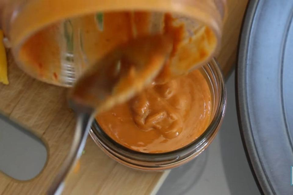 spicy peanut sauce being dolloped into a jar