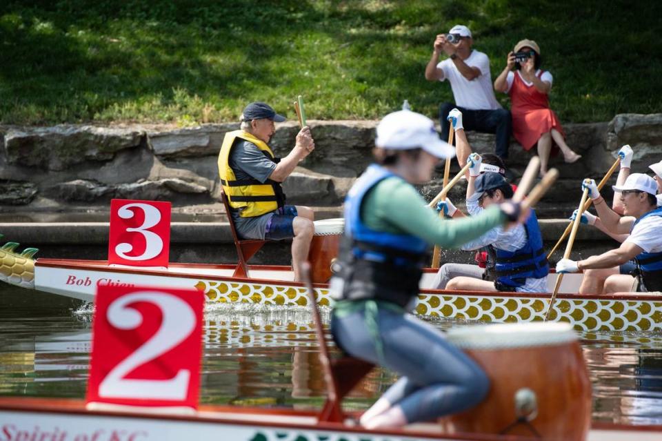 Spectators photograph two neck-and-neck teams during a dragon boat race at the 35th annual Kansas City Dragon Boat Festival.