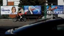 A woman rides her bicycle in front of election banners in Warsaw