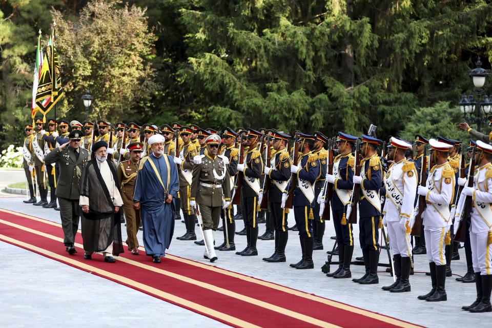 In this photo released by the office of the Iranian Presidency, Oman's Sultan Haitham bin Tariq Al Said, on carpet front right, reviews an honor guard as he is welcomed by Iranian President Ebrahim Raisi, on carpet front left, during an official welcoming ceremony at the Saadabad Palace in Tehran, Iran, Sunday, May 28, 2023. Oman has a long record of being a key broker between Iran and the West, amid volatile regional tensions. (Iranian Presidency Office via AP)