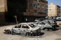 People gather next to burnt cars after yesterday's clashes in Tripoli