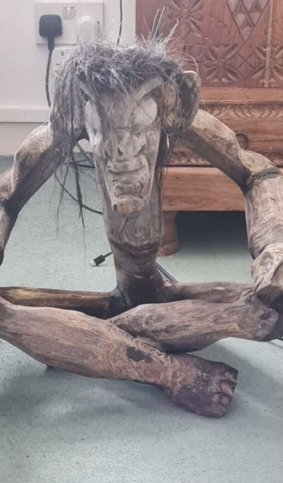 cross-legged wooden statue with dried grassy hair