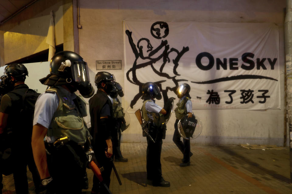 Policemen in riot gear stand guard during a face off with protesters in Hong Kong, Wednesday, Aug. 14, 2019. German Chancellor Angela Merkel is calling for a peaceful solution to the unrest in Hong Kong amid fears China could use force to quell pro-democracy protests. (AP Photo/Vincent Yu)