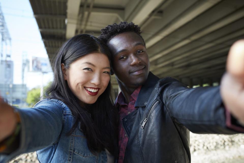 A couple takes a selfie under a bridge