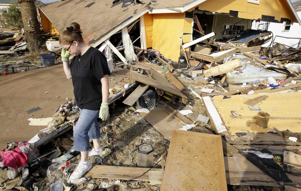 FILE - In this Sept. 24, 2008, file photo, Gina Hadley walks through what’s left of her home in the aftermath of Hurricane Ike in Galveston, Texas. The Ike Dike is a proposed coastal barrier that would protect the Houston-Galveston region, including Galveston Bay, from hurricane storm surge. The project was conceived by Bill Merrell, a professor in the Marine Sciences Department at Texas A&M University at Galveston and a former president of the school, in response to the extensive surge damage caused by Hurricane Ike in September of 2008. (AP Photo/David J. Phillip, File)