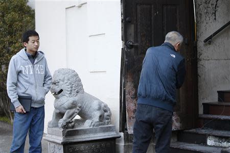 People look into the damaged front door of the Chinese consulate after an unidentified person set fire to the main gate in San Francisco, California January 2, 2014. REUTERS/Stephen Lam