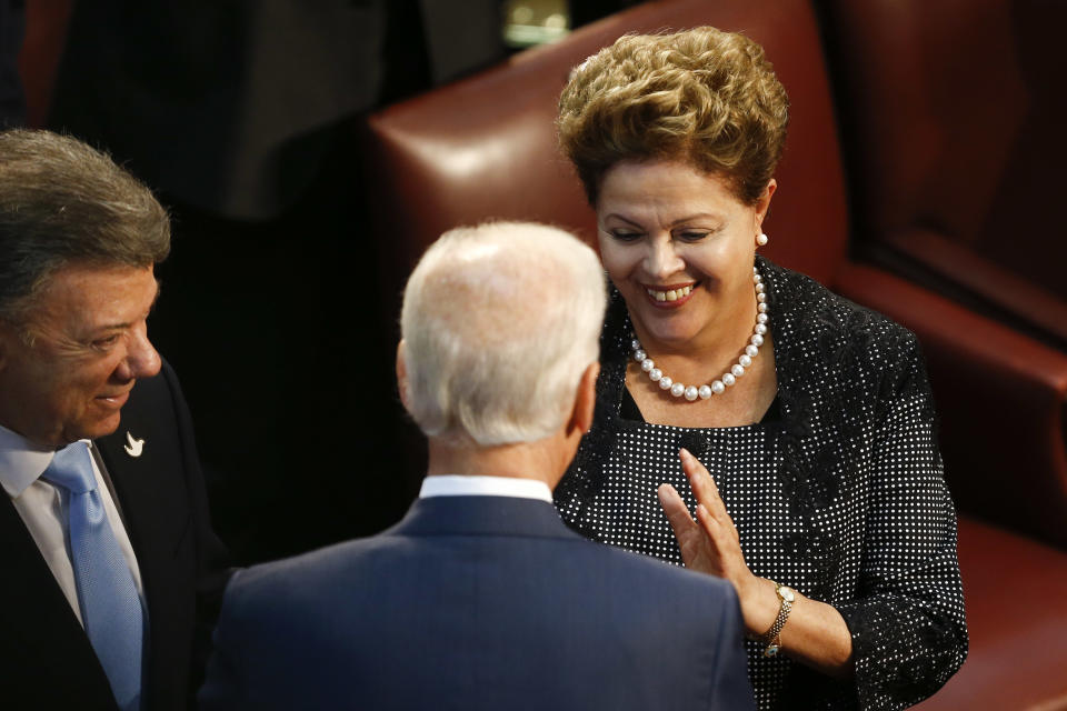 Brazilian President Dilma Rousseff, right, talks with Vice President Joe Biden embrace as Colombian President Juan Manuel Santos watches, before the start of Michelle Bachelet's swearing-in ceremony as Chile's president, in the Chilean Congress in Valparaiso, Chile, Tuesday, March 11, 2014. (AP Photo/Victor R. Caivano)