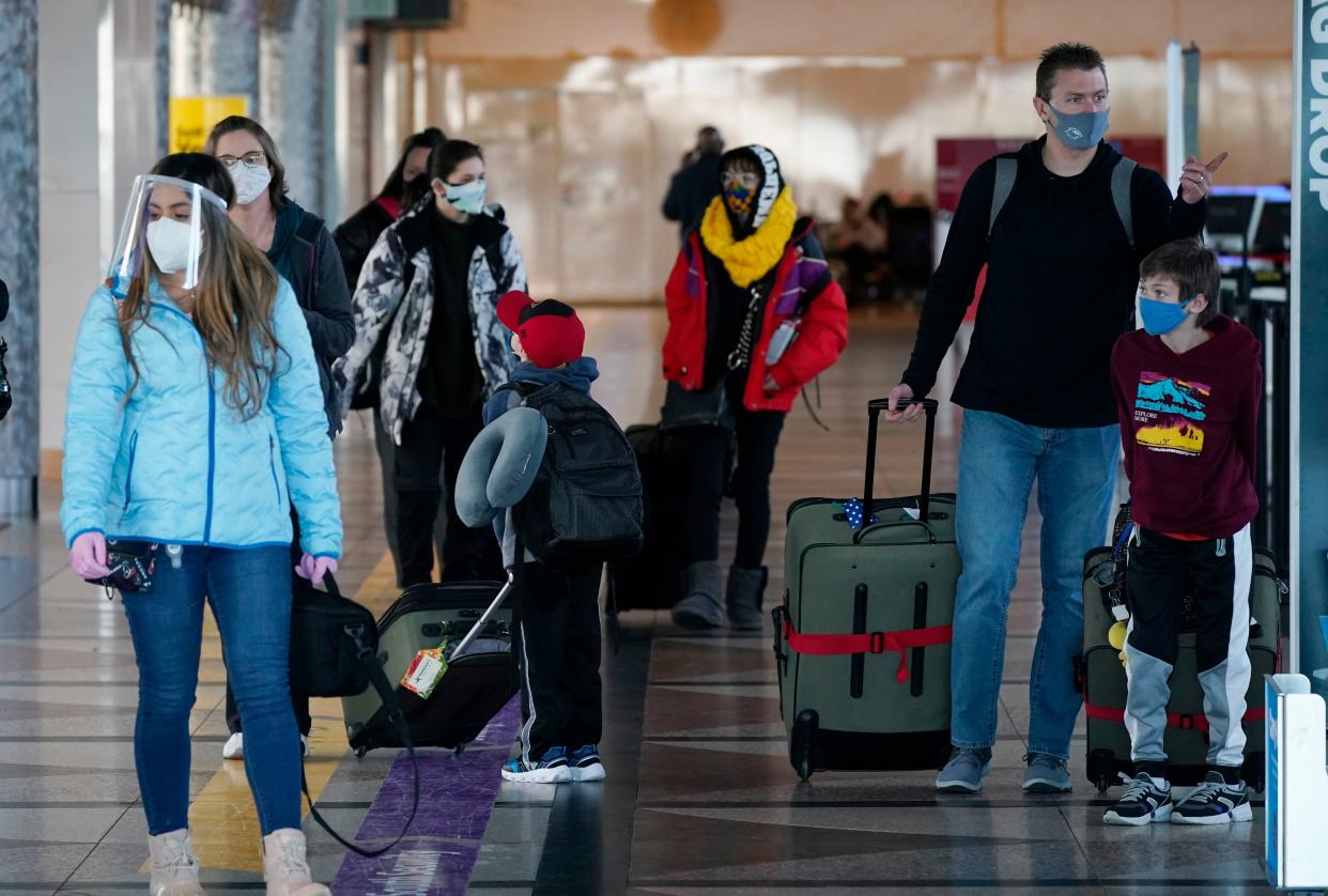 Travelers wear face masks while checking in at the ticket counter of Frontier Airlines in the main terminal of Denver International Airport.