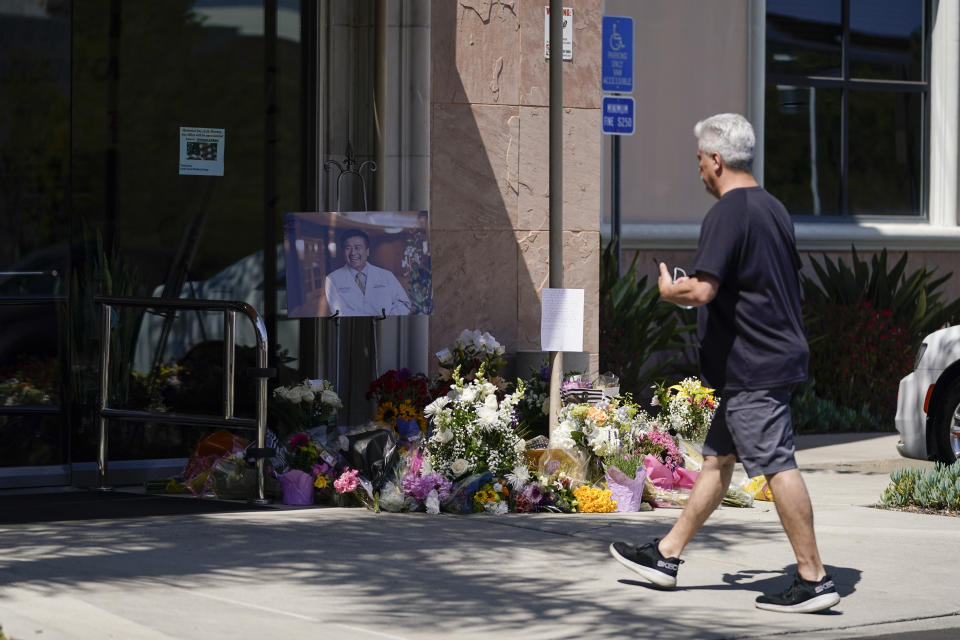 Ira Angustain, pastor at Kingdom Covenant Church, passes by a memorial honoring Dr. John Cheng outside his office building on Tuesday, May 17, 2022, in Aliso Viejo, Calif. Angustain said he was in contact with Cheng, 52, shortly before he was killed in Sunday's shooting at Geneva Presbyterian Church. (AP Photo/Ashley Landis)