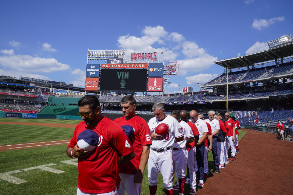 Washington Nationals manager Dave Martinez, left, and others observe a moment of silence for Los Angeles Dodgers broadcaster Vin Scully before a baseball game against the New York Mets at Nationals Park, Wednesday, Aug. 3, 2022, in Washington. The Hall of Fame broadcaster, whose dulcet tones provided the soundtrack of summer while entertaining and informing Dodgers fans in Brooklyn and Los Angeles for 67 years, died Tuesday night. He was 94. (AP Photo/Alex Brandon)